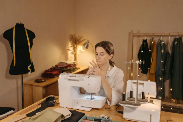 A focused woman seamstress seated at a sewing machine in a fashion studio.